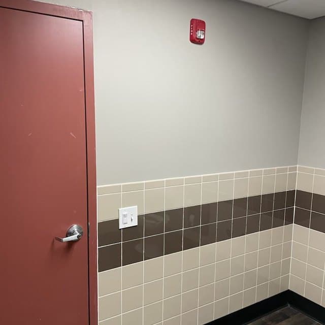 Commercial corridor with a tiled dado rail and a red fire door